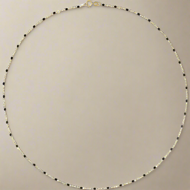 
                      
                        A delicate, thin necklace with alternating small black enamel beads and gold beads from Pear. is displayed on a neutral background. This Enamel Satellite Bracelet by Pear., circular in shape with a small clasp at the top, has a minimalist design that exudes elegance and simplicity.
                      
                    