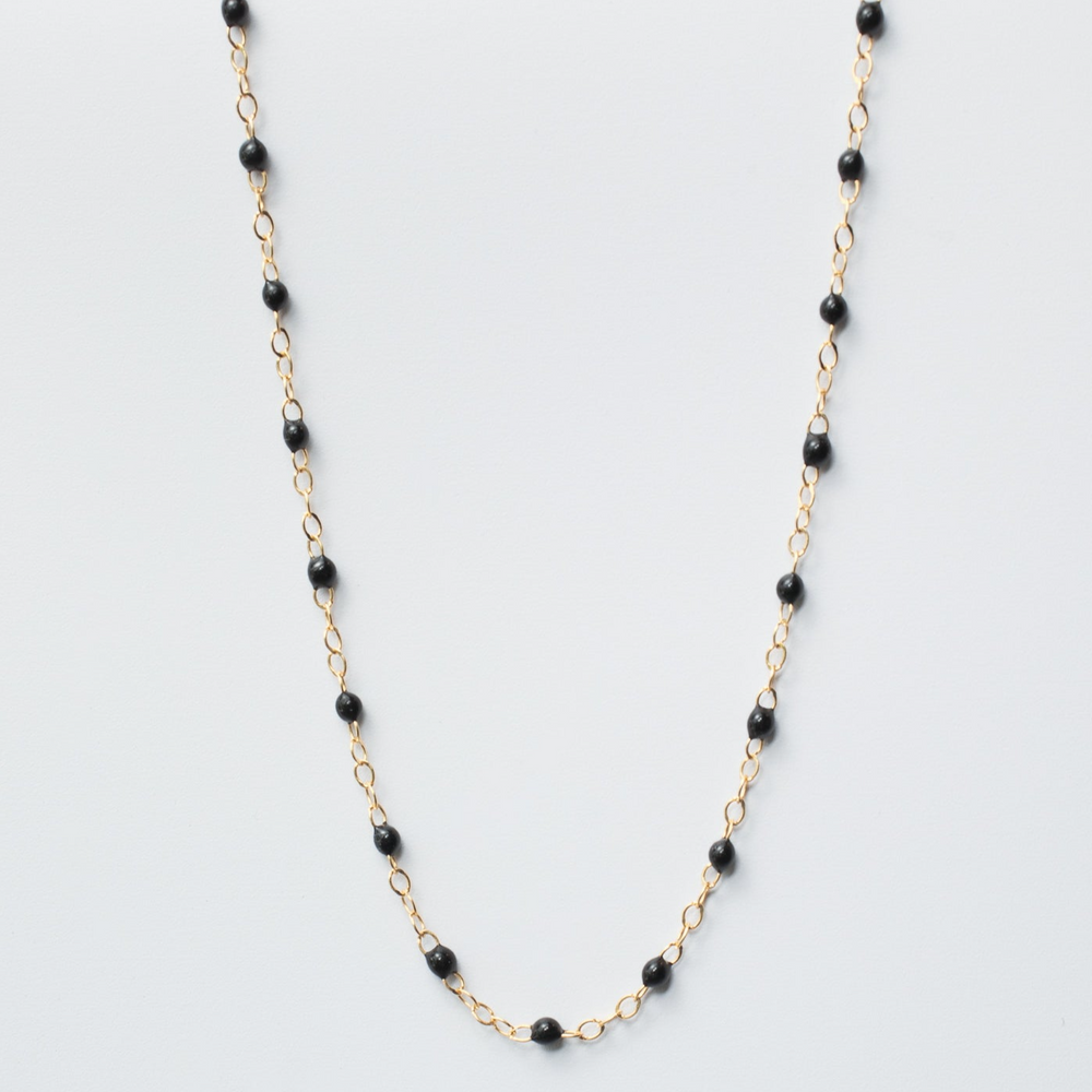 
                      
                        A delicate gold chain necklace with small round black enamel beads evenly spaced throughout. This simple yet elegant design, reminiscent of the Pear Enamel Satellite Bracelet, creates a stylish and versatile accessory. The necklace is displayed against a plain white background.
                      
                    