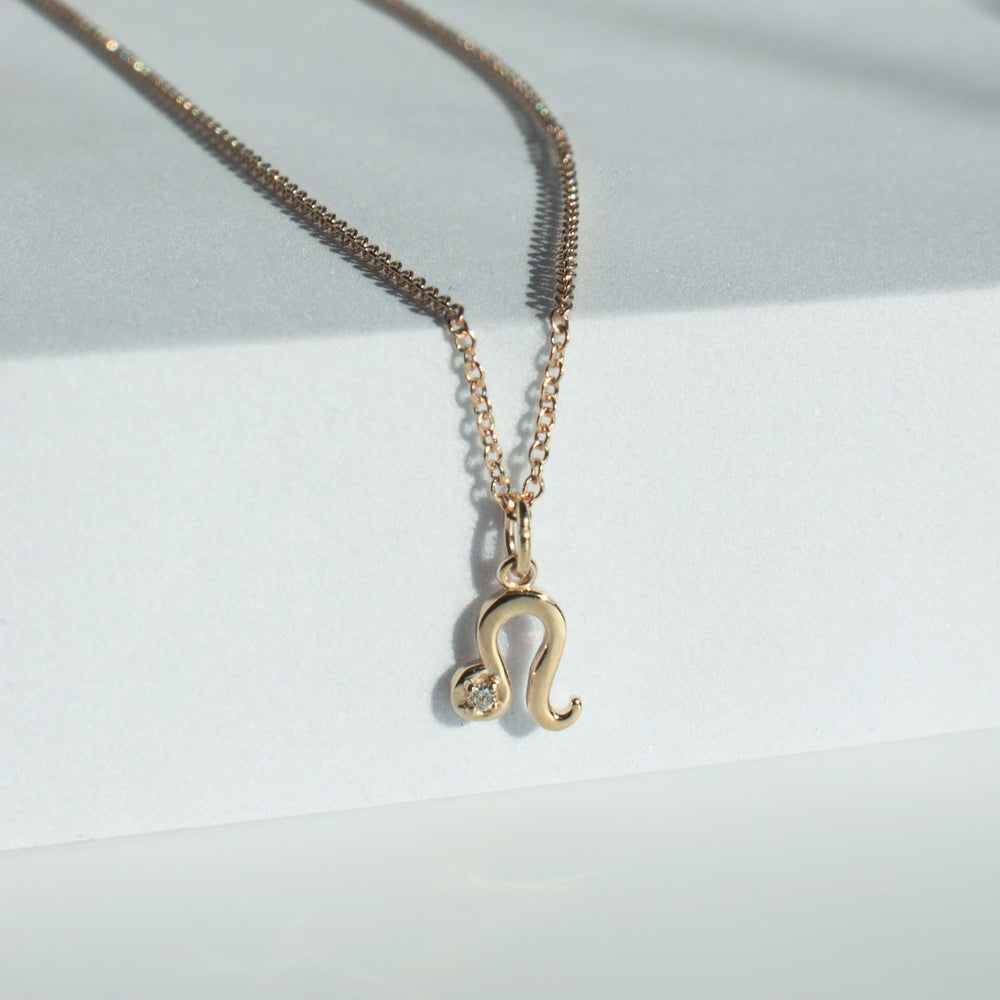 
                      
                        The Diamond Zodiac Necklace by Pear is a delicate gold necklace that showcases a pendant shaped like the Leo zodiac sign. A small, round diamond accent is embedded into the lower curve of the symbolic pendant. It is displayed on a light-colored, sleek surface under soft lighting and features an adjustable cable chain to ensure a perfect fit.
                      
                    