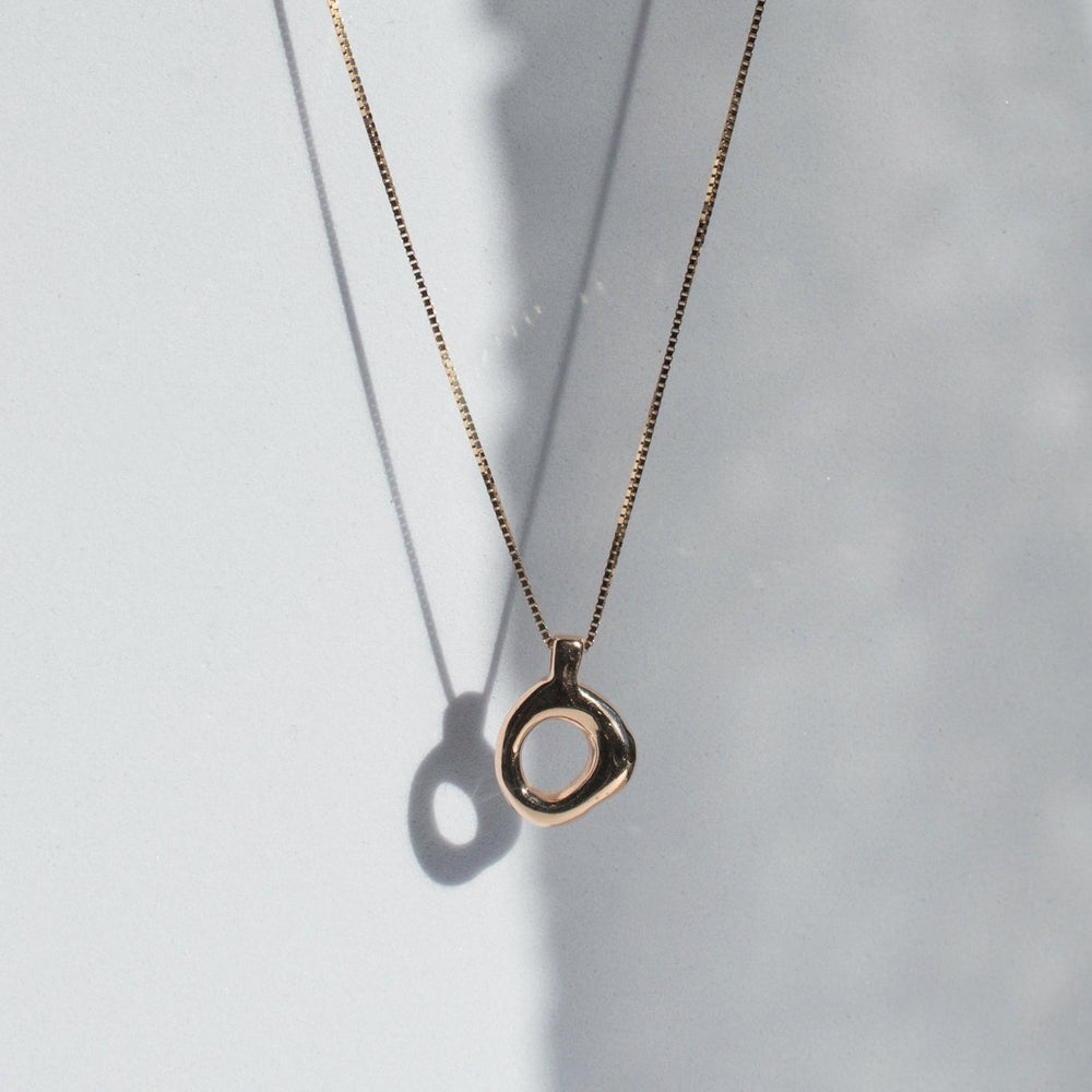 
                      
                        The Pear Odette Necklace features a thin chain with an irregularly shaped, open circular pendant that casts a delicate shadow on a light grey background. This piece of timeless jewelry combines minimalist and elegant aesthetics, making it a perfect addition to any collection.
                      
                    