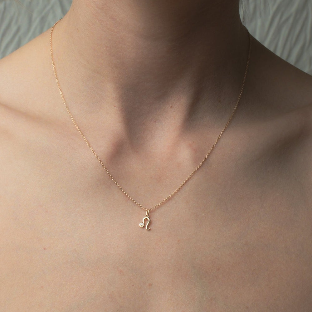 
                      
                        Close-up of a person wearing Pear's Diamond Zodiac Necklace, featuring a delicate gold chain with a small, diamond-studded zodiac pendant. The adjustable cable chain rests just below the collarbone, against their bare skin. The background is neutral and out of focus.
                      
                    