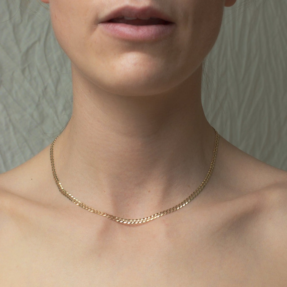 
                      
                        A close-up image shows a person wearing a Pear Curb Chain Necklace made of 14K Solid Yellow Gold around their neck. The background appears to be a textured, light-colored surface. The person's shoulders and part of their mouth are visible, with natural lighting highlighting the necklace's daily wearability.
                      
                    