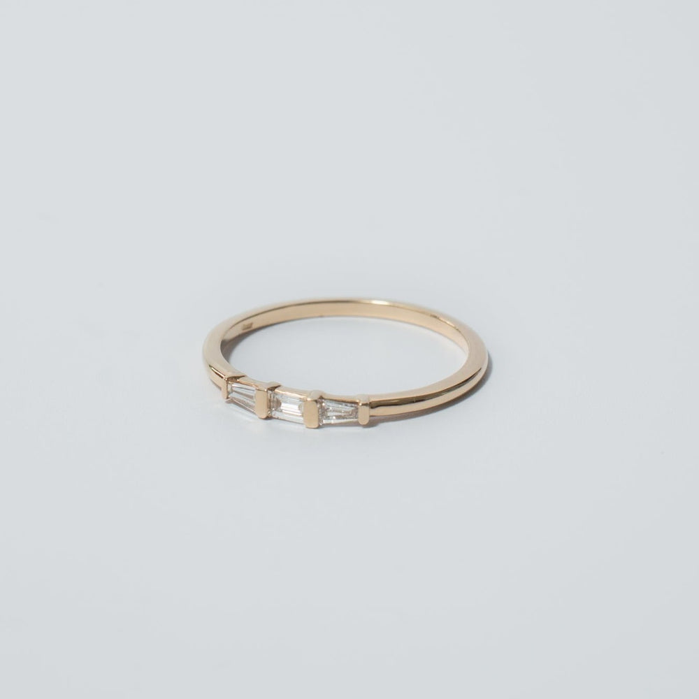 
                      
                        The Edith Diamond Ring by Pear is a delicate gold piece showcasing three baguette diamonds centrally arranged, evenly spaced and aligned horizontally. The image, set against a plain white background, accentuates the jewelry's simplicity and elegance.
                      
                    