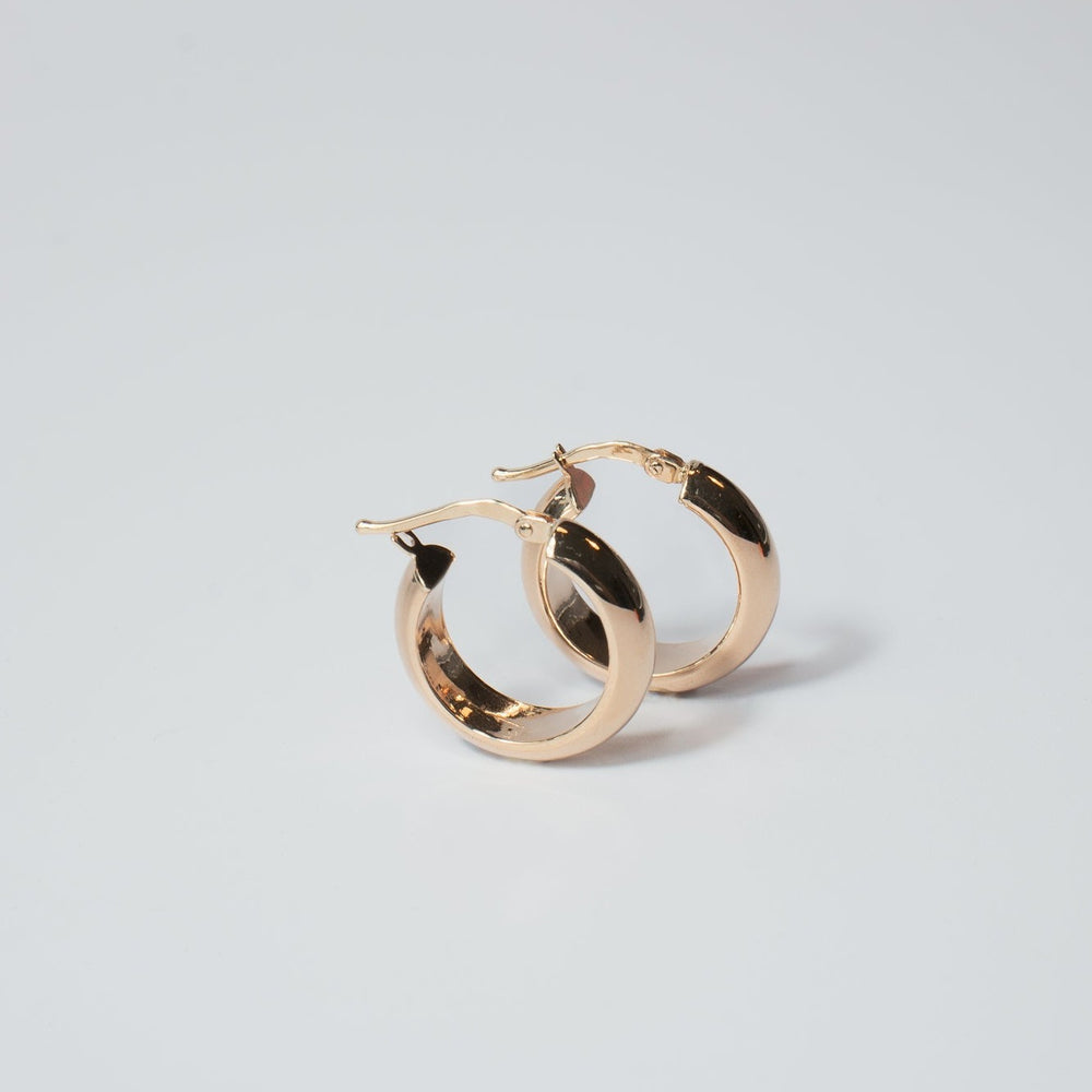 
                      
                        A pair of Pear.'s Solid Chunky Hoops with smooth, polished surfaces, placed on a light gray background. The earrings are slightly overlapping, with the clasps open, displaying their round shape and shiny appearance.
                      
                    