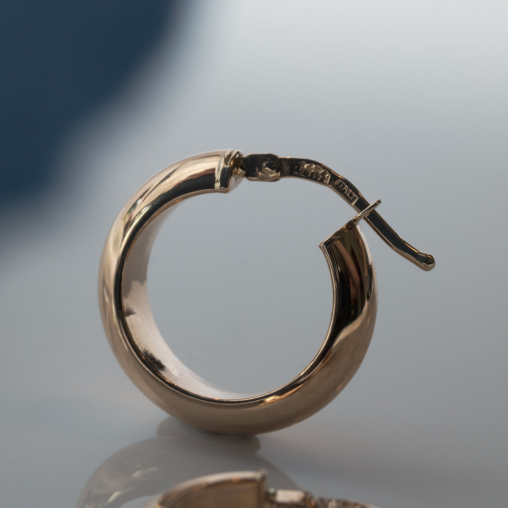 
                      
                        Close-up of a single Pear Solid Chunky Hoop earring with a smooth, polished surface. The solid half hoop is circular and features a hinged clasp for easy wearing. The background is blurred, directing all attention to the elegant lightweight earring from Pear.
                      
                    