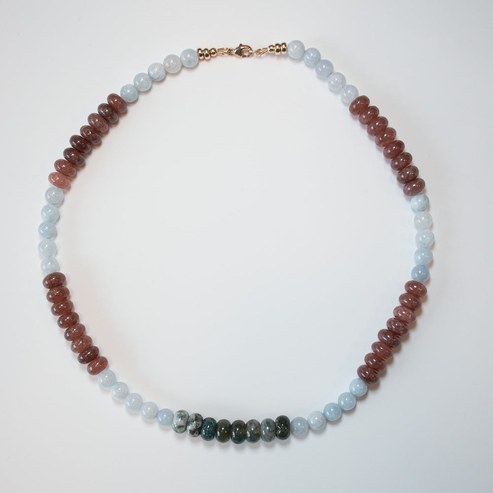 Introducing the "Cordelia Bead Necklace" by Pear: a beautifully crafted piece featuring alternating sections of red, milky blue jade, and green moss agate beads, finished with an elegant gold clasp. It is showcased against a simple white background for maximum impact.