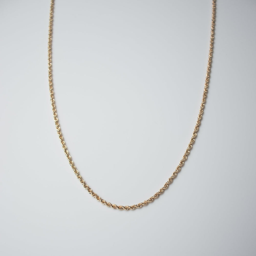 Placed against a plain white background, the Round Rope Chain necklace by Pear. beautifully displays its intricate twisted design and delicate shine, crafted in 14K yellow gold.