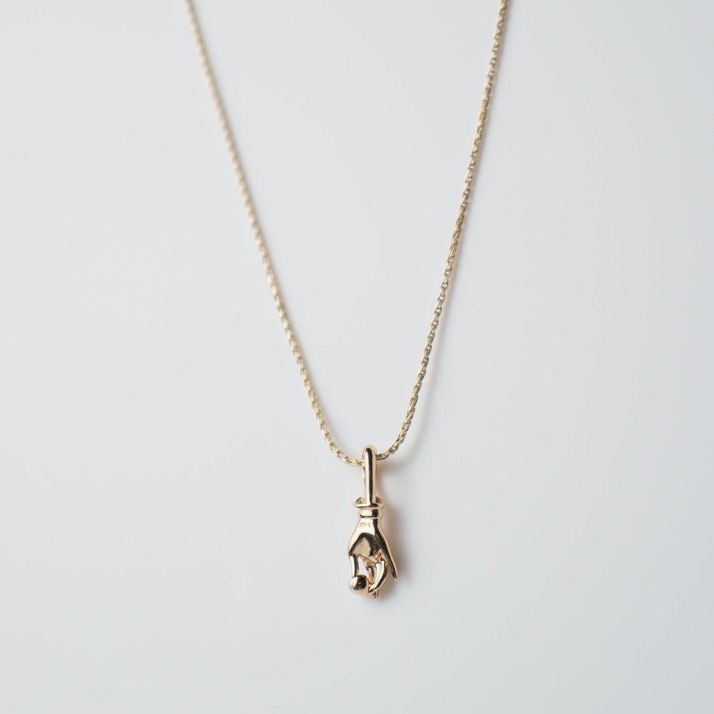 
                      
                        The Pear. Pearl Buddha Hand Necklace, crafted from delicate 14K yellow gold, features a small hand-shaped pendant adorned with an elegant Buddha charm and is showcased against a plain, light-colored background.
                      
                    