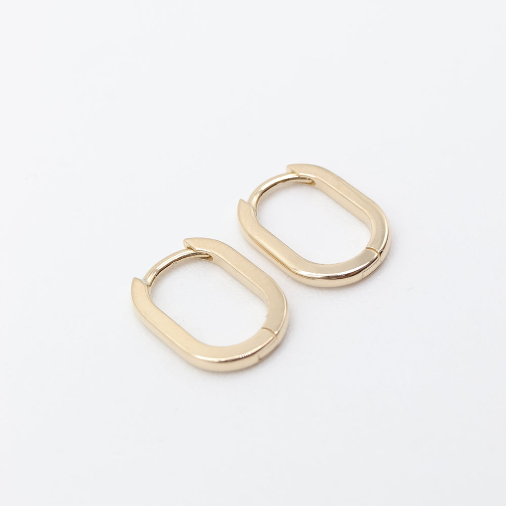 
                      
                        The Pear Elliot Hoops, featuring a pair of small, elongated oval-shaped gold hoop earrings with smooth, polished surfaces and a latch-style hinge, are displayed against a plain white background.
                      
                    