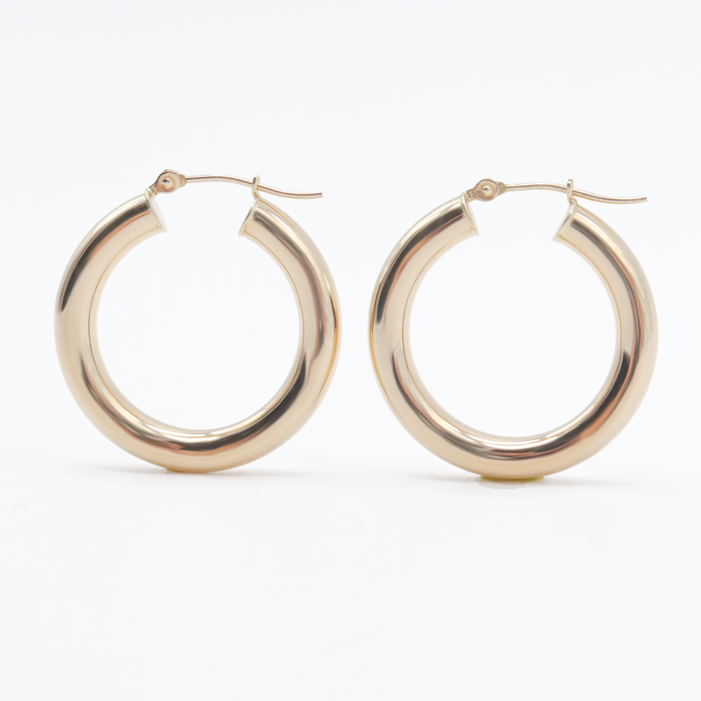 
                      
                        A pair of Pear. Thick Tube Hoops crafted from shiny, solid 14K gold with a polished finish. Featuring a classic circular shape, these earrings are photographed against a plain white background to emphasize their simplicity and elegance. The lightweight latch-back closures are clearly visible at the top, highlighting their practical design.
                      
                    