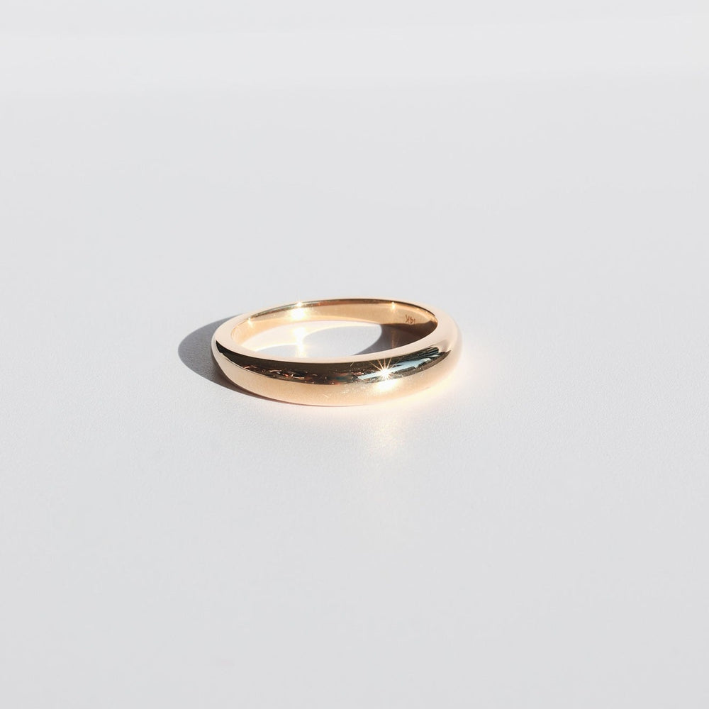 
                      
                        A simple, polished 14K Yellow Gold Dome Ring from Pear rests on a smooth white surface. Light catches the ring's curve, creating a small bright reflection. Perfect for daily layering, the minimalist background enhances its elegance.
                      
                    